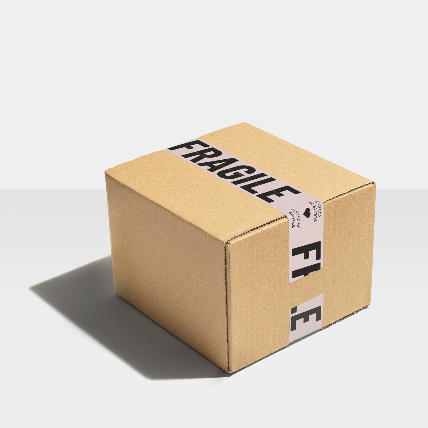 Large shipping box sealed with modern bold black text sealing tape with the words "Fragile, Please Be Gentle" printed on it.