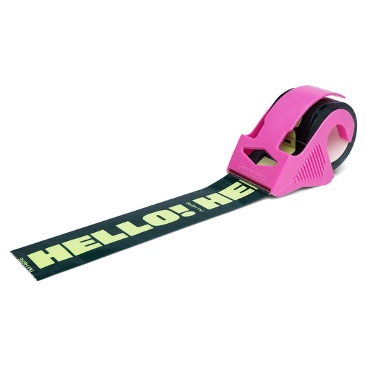 Green packing tape with bold mint “Hello! I’m Here” text, shown in a bright pink mini dispenser—playful and vibrant shipping tape designed to make small business packages stand out.