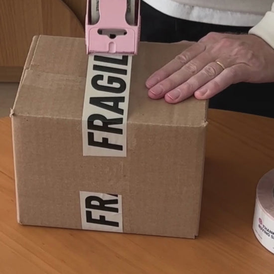 A man is taping a box with Fragile packaging tape.
