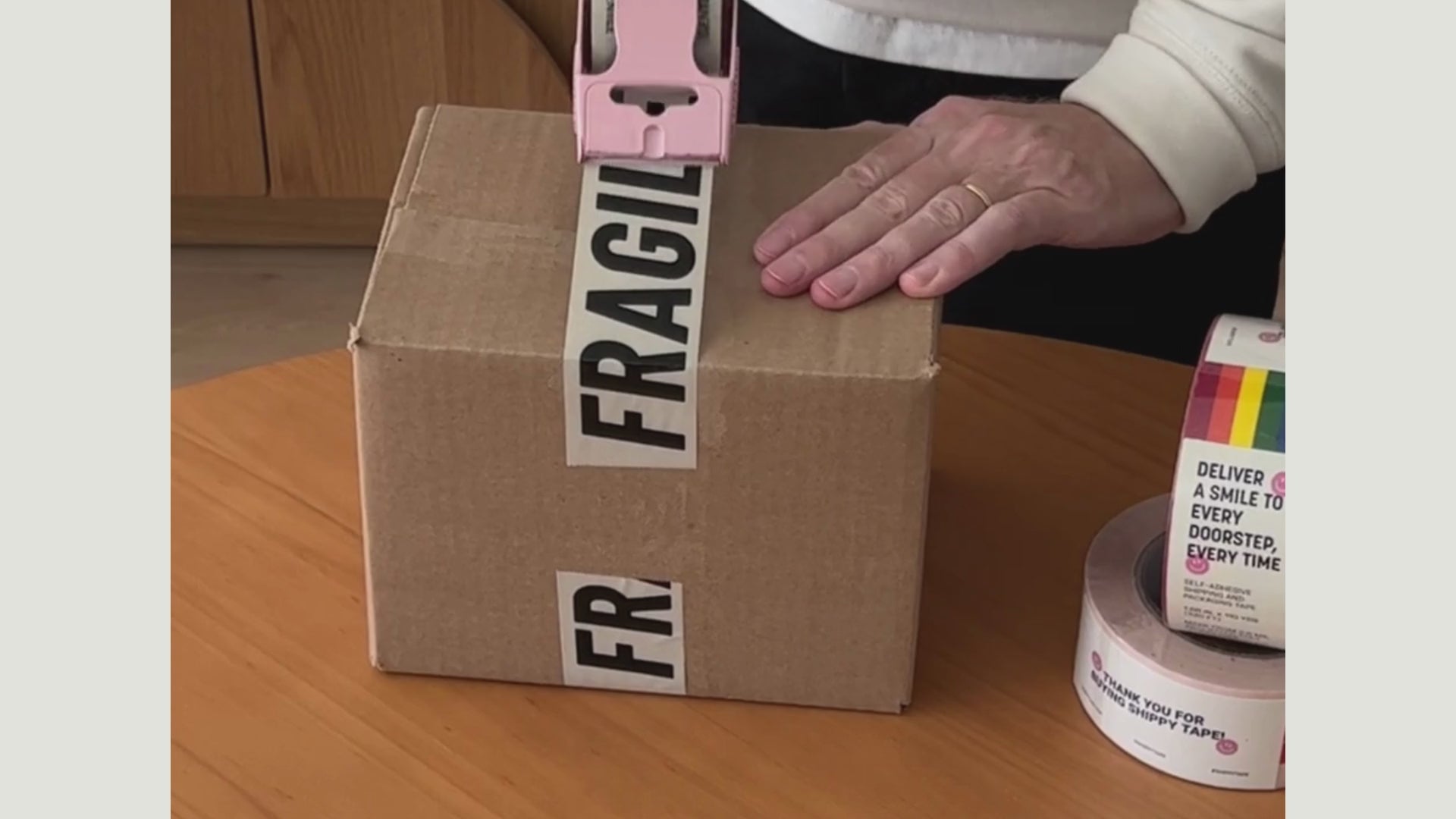 A man is taping a box with Fragile packaging tape.