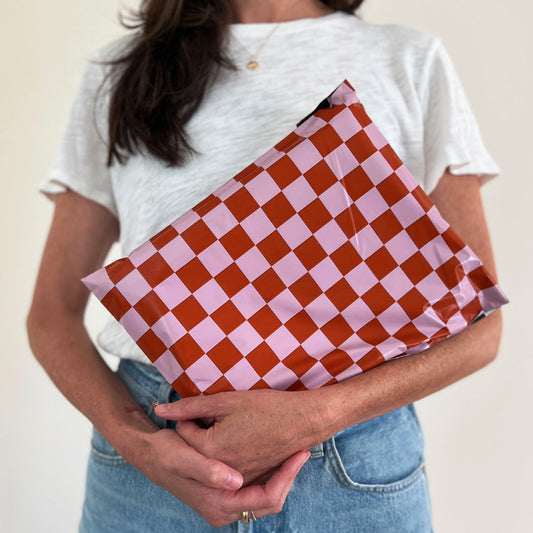 Person holding a cute pink and red checkered poly mailer bag for sending Poshmark orders.