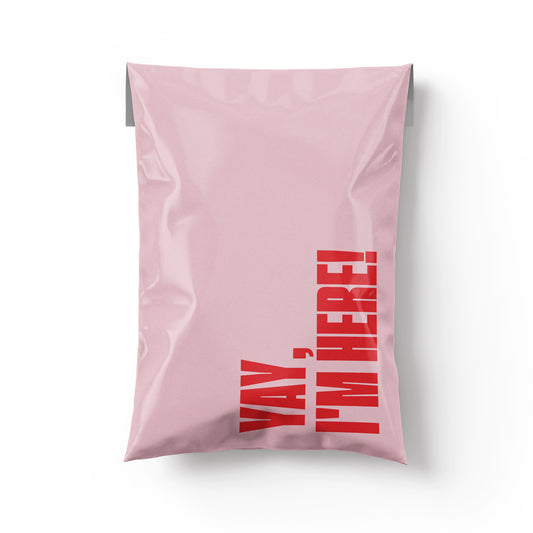 Pink pillow with red text 'Yay, I'm here!' on a white background