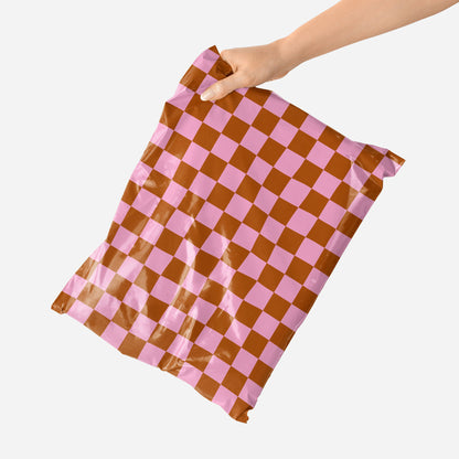 Checkered shipping bag with pink and red pattern held by a hand on a white background