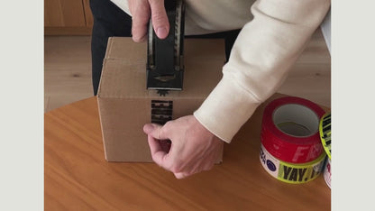 using tape dispenser to add tape to box yay i'm here clear shipping tape with black text